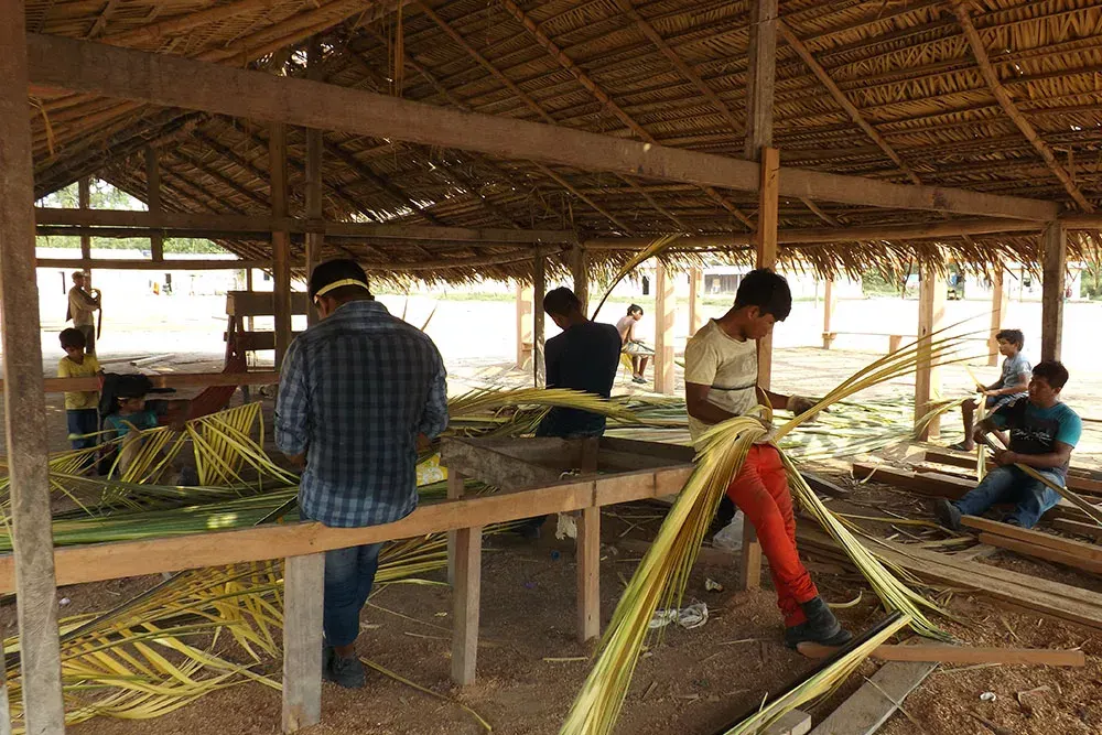 Men working on the wood and thatch structure of the Ngàb